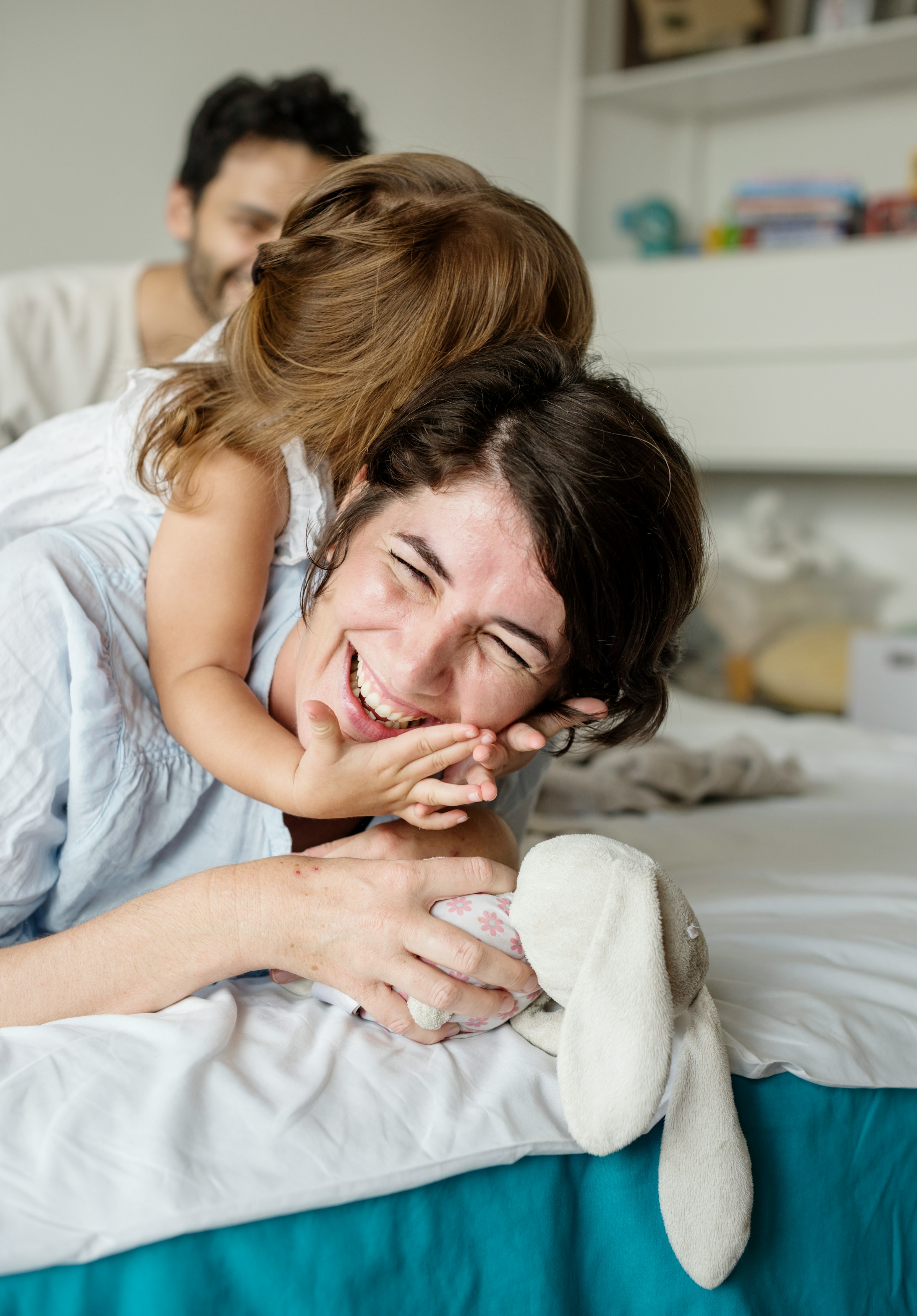 Caucasian family playing together on the bed.