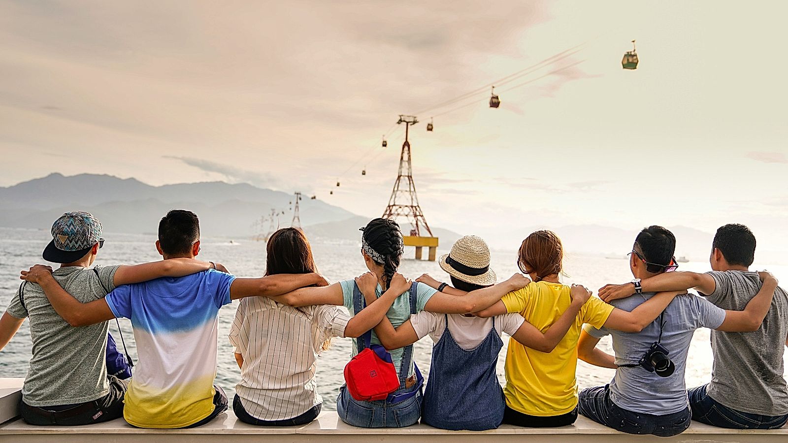 People holding shoulders sitting on wall.