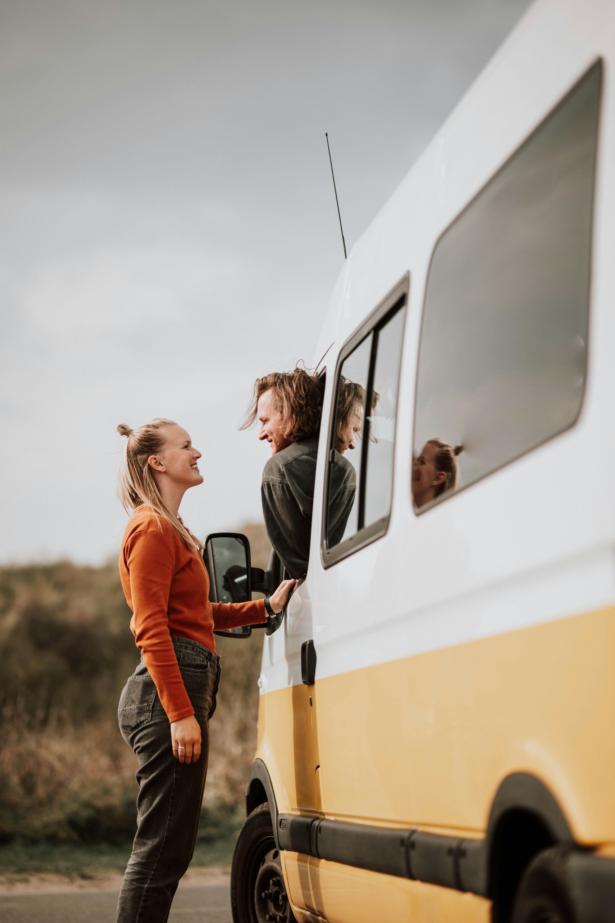 A couple standing next to a van.