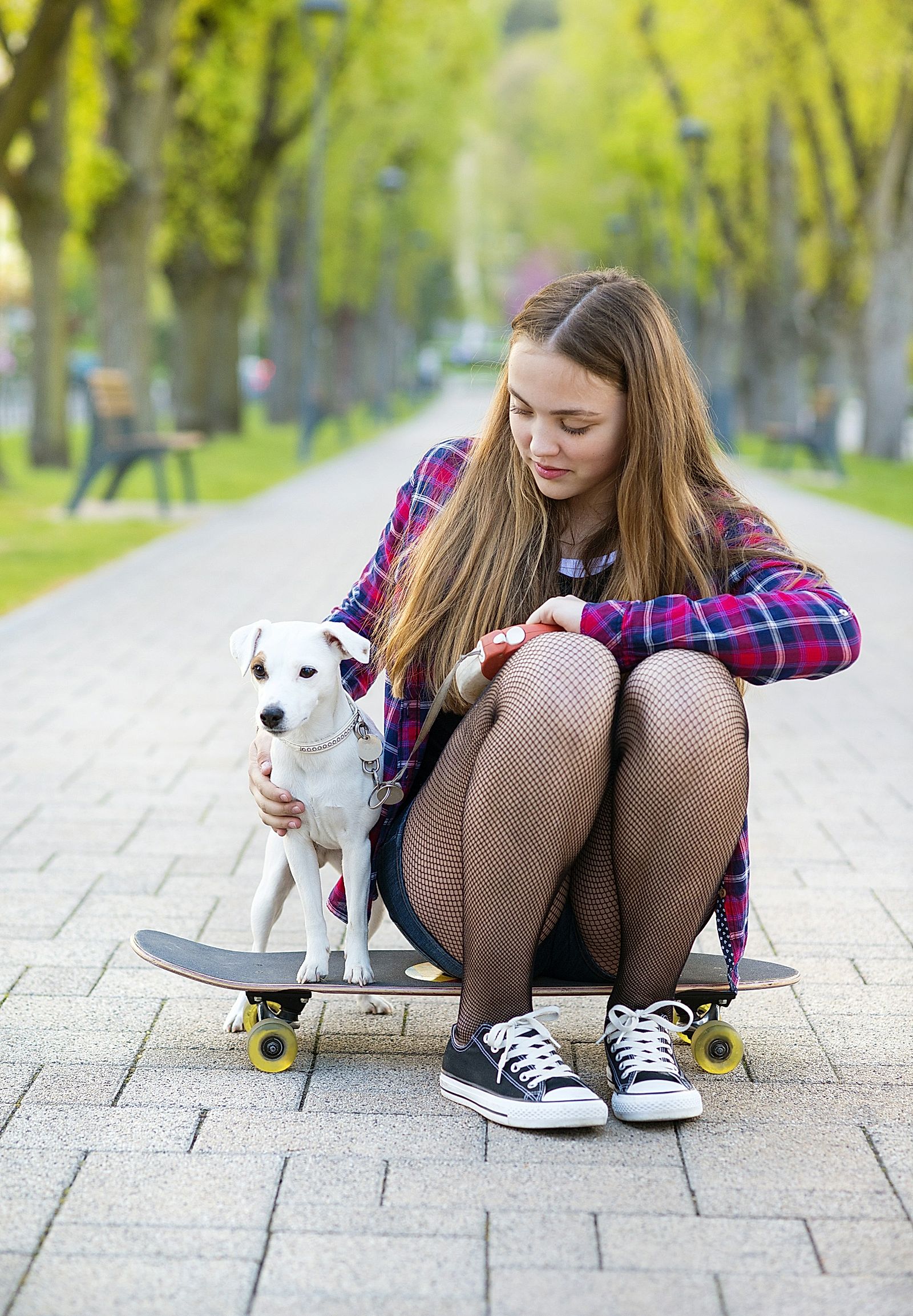 Teenage girl on skateboard with her dog.