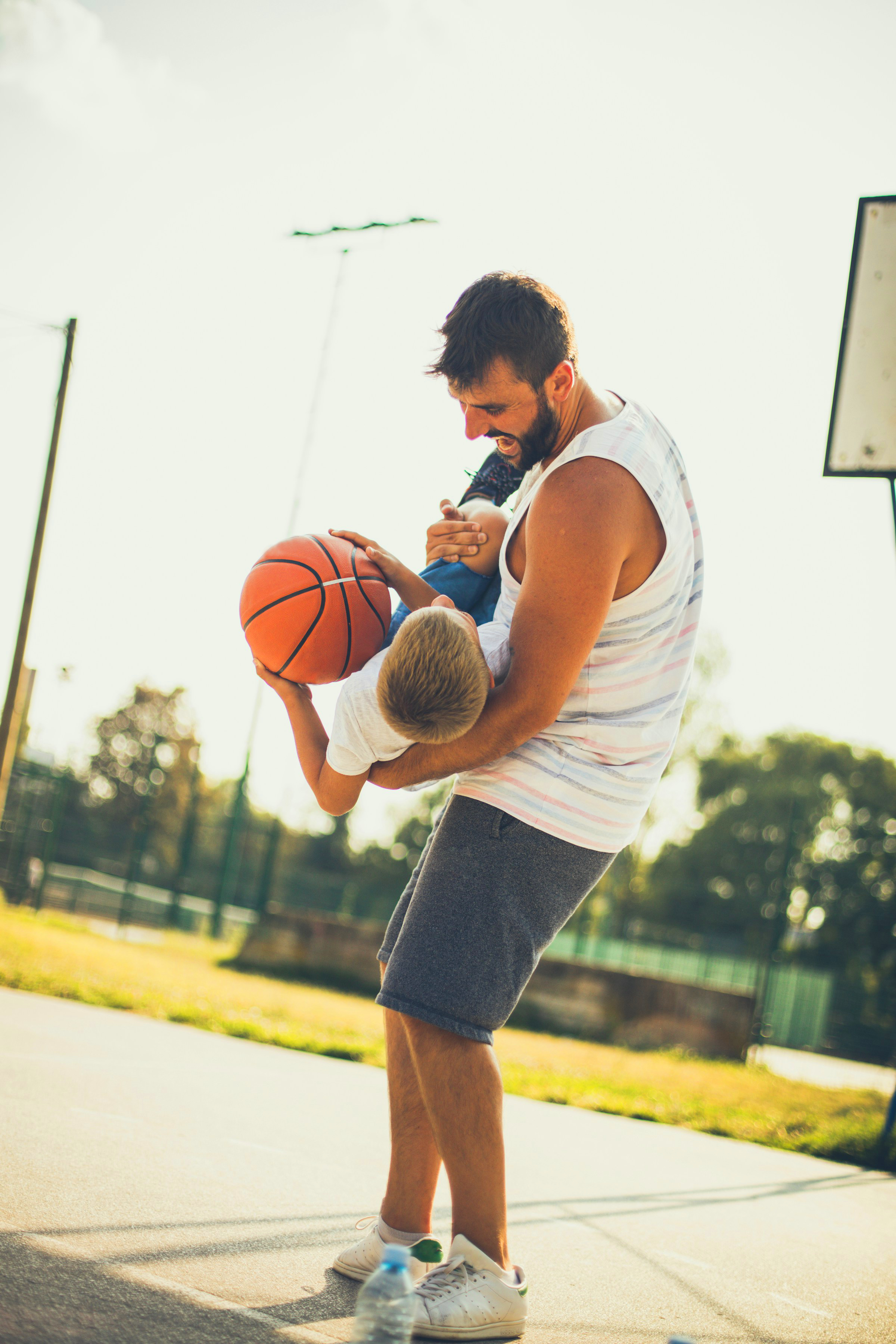 Summer day. Father and son on basket court.